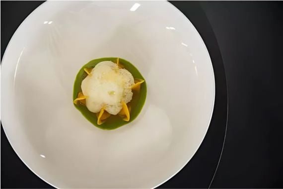 A delicate arrangement of pasta in green sauce, topped with a light foam for a refined touch.