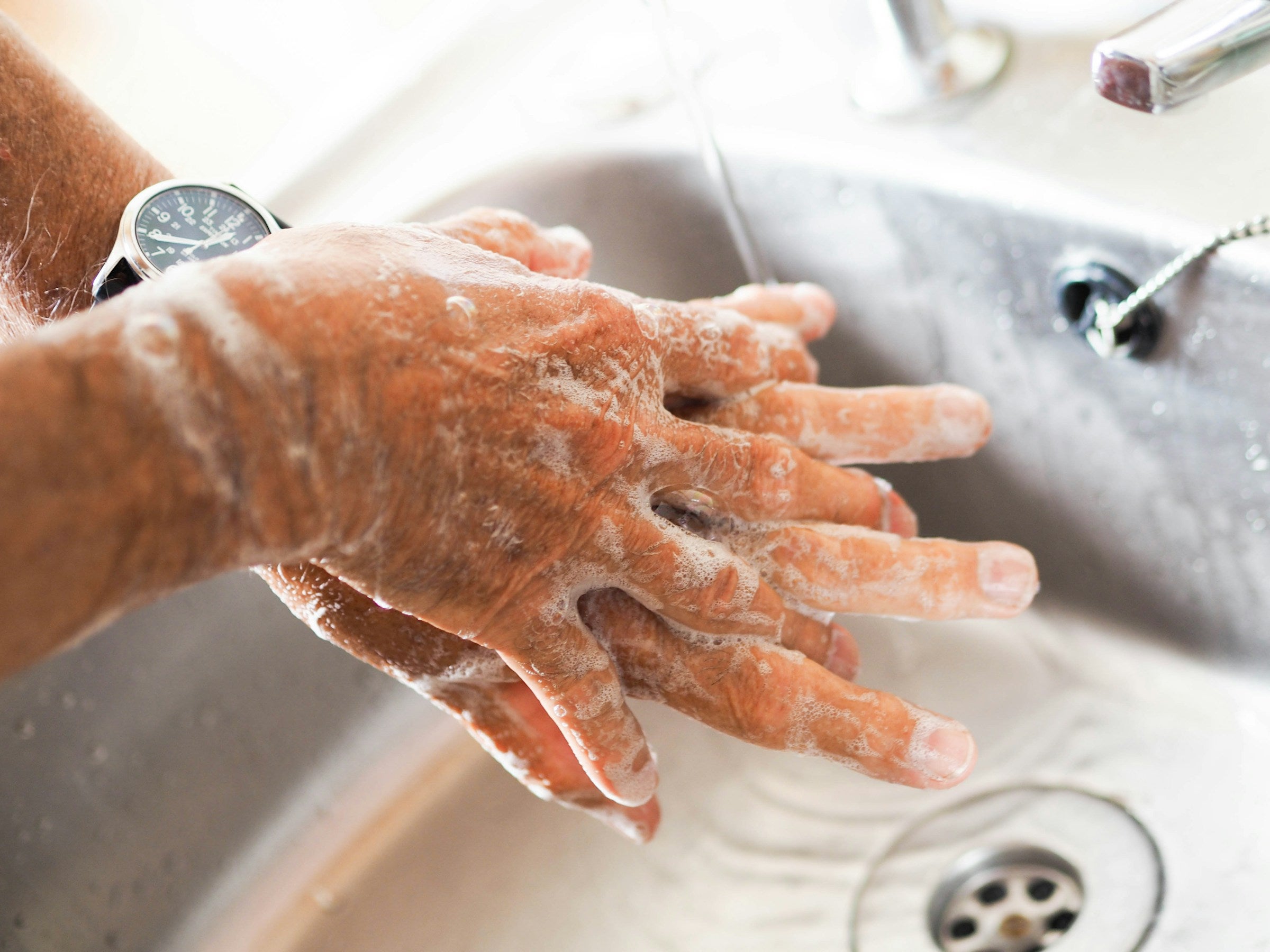 A person thoroughly washing hands under a running tap with soap