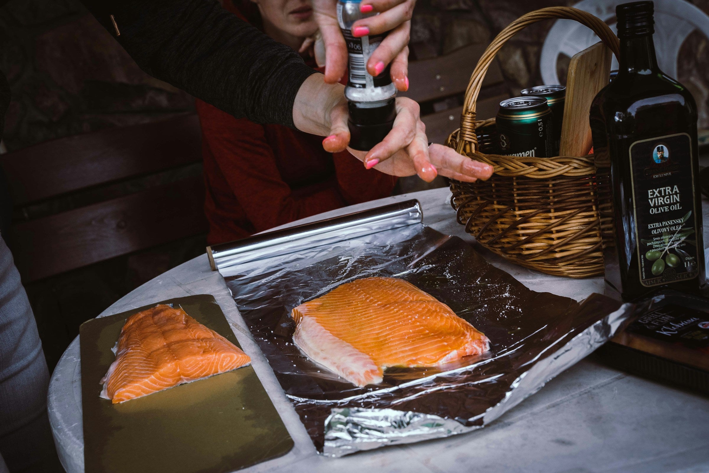 A home cook seasoning a side of salmon set on a piece of foil before baking.