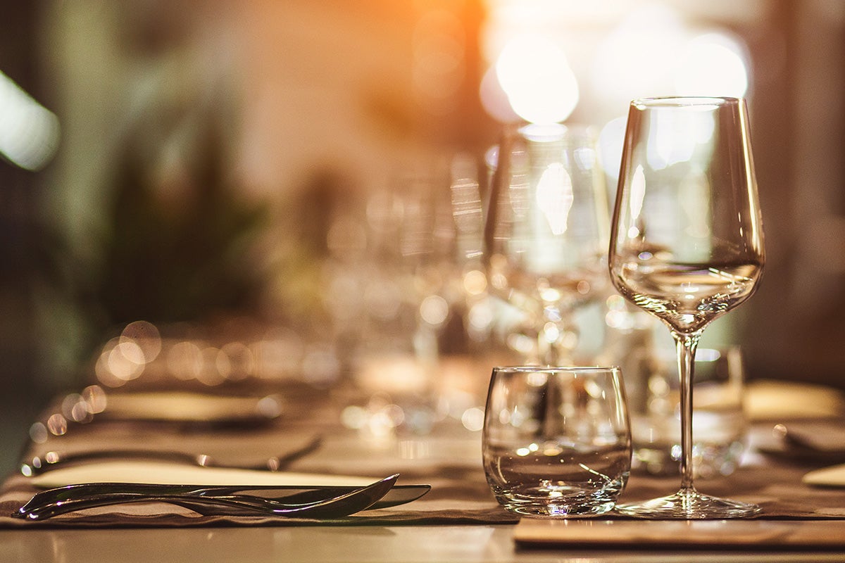 Restaurant tables with glasses and cutlery.