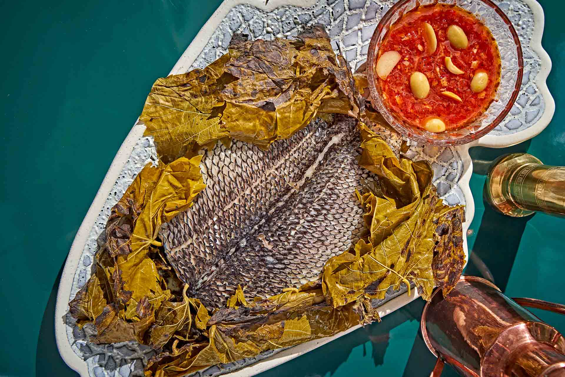 A dish filled with grilled fish and cooked green leaves