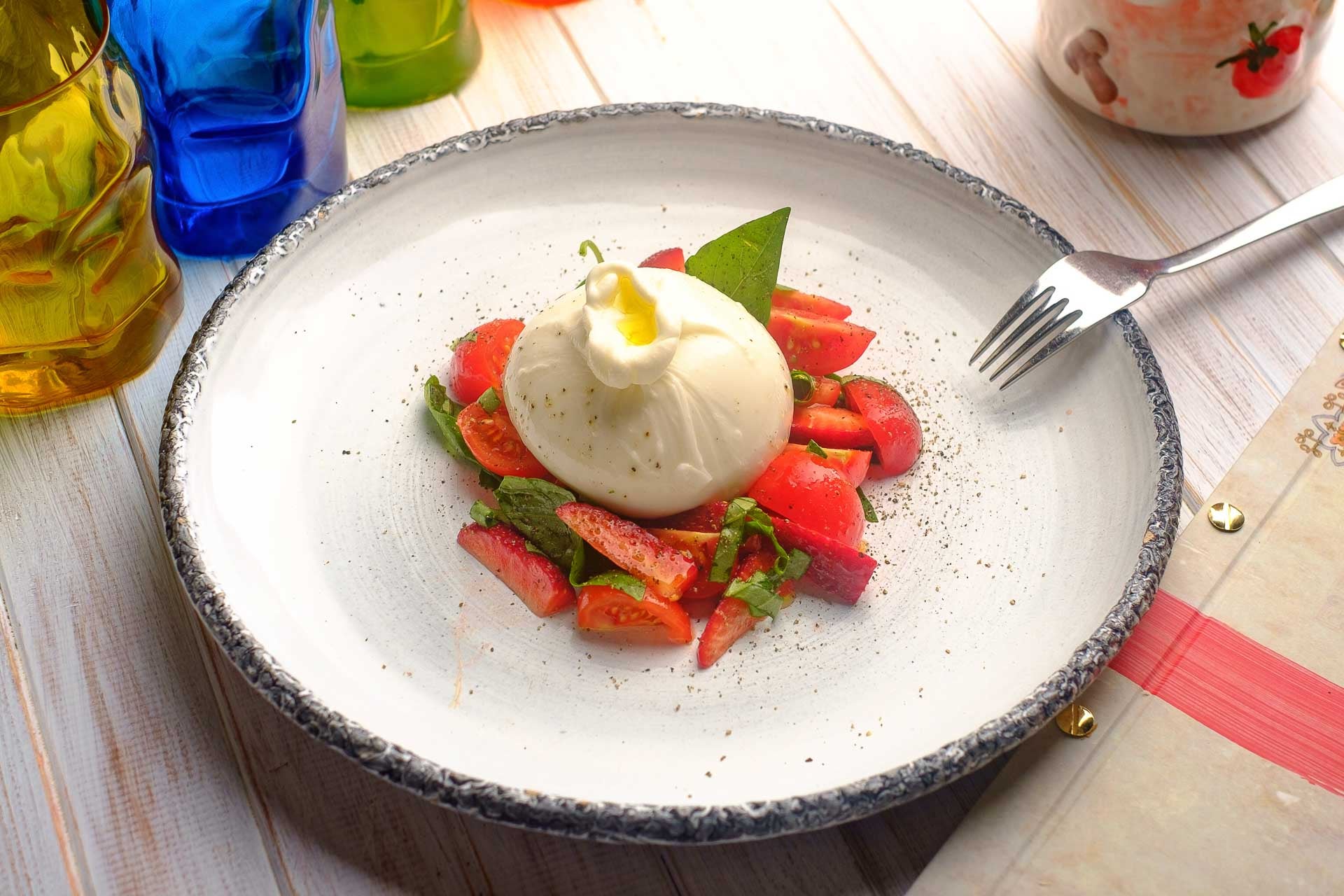 a dish of burrata plated on top of fresh sliced strawberrries