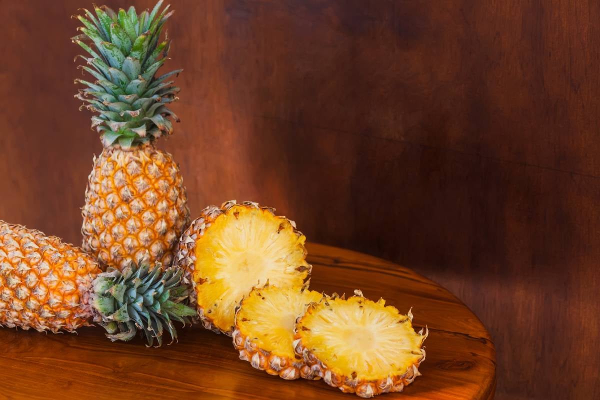 Table with entire and sliced tropical Pineapple fruit
