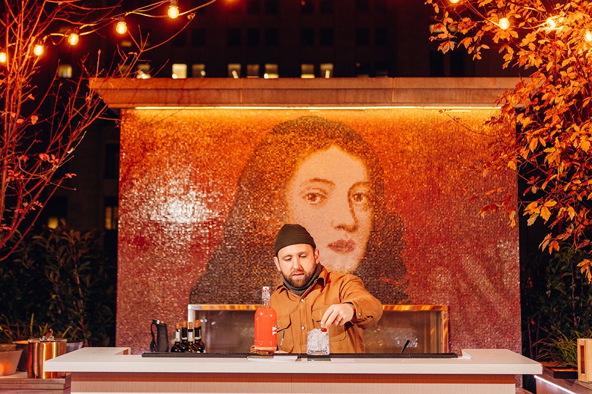 man making cocktails at bar with background image of woman's face