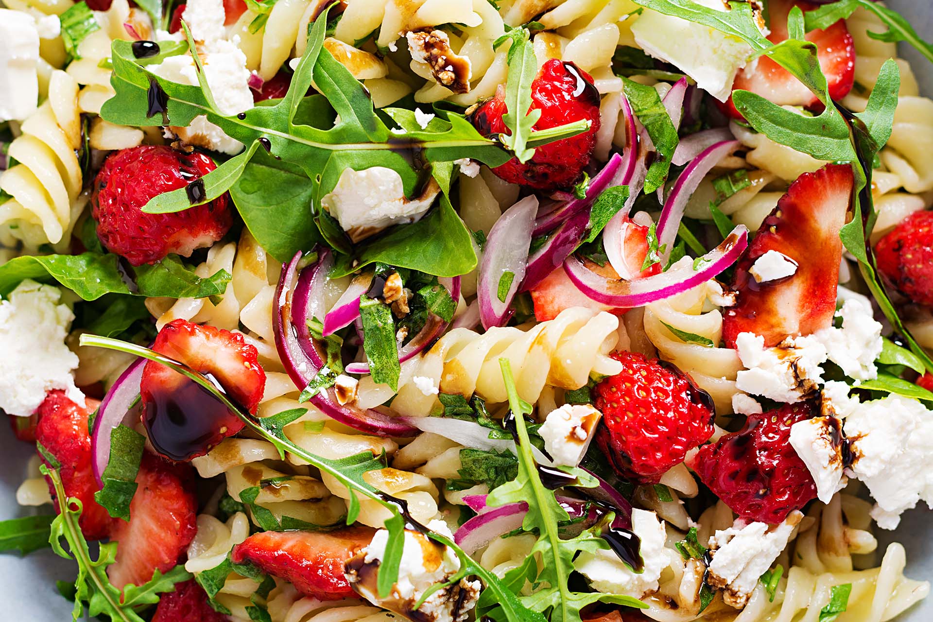 Pasta and strawberry salad with feta cheese, red onion and balsamic sauce