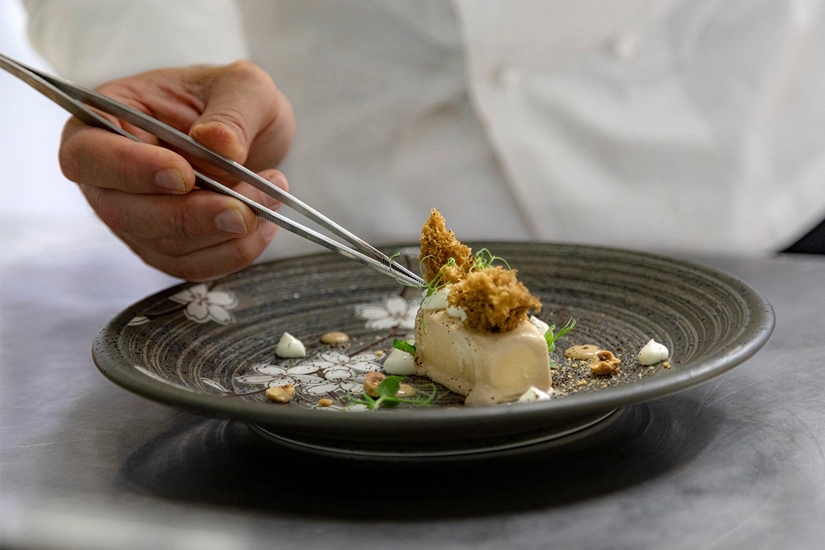 A chef plating a delicate dish with tweezers.