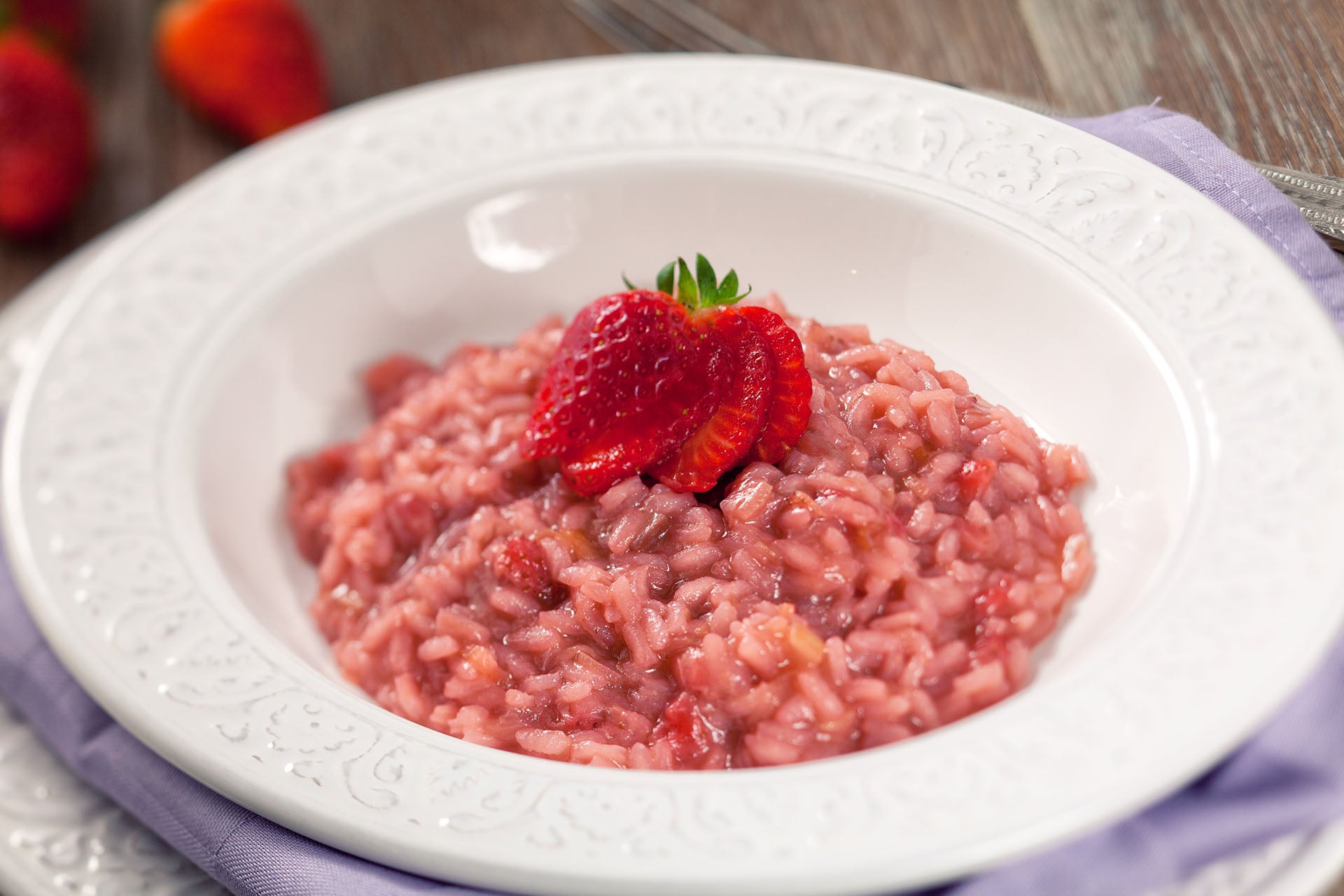 Risotto with strawberries in a white bowl with a fresh strawberry on top