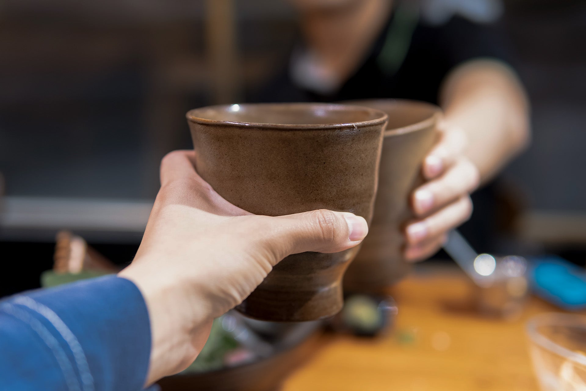 Two hand holding a terracotta glass and cheering