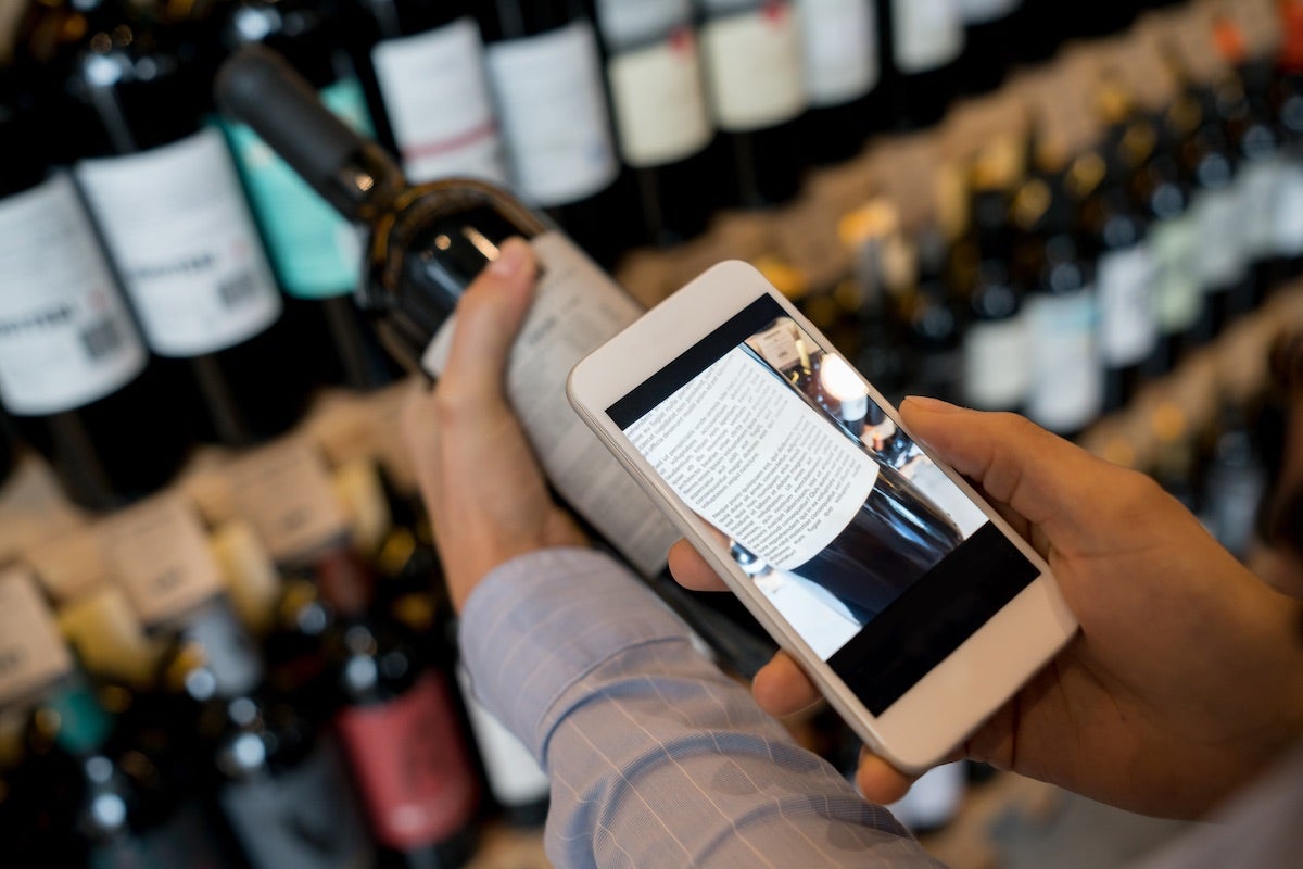 Woman checking wine label using wine app on smartphone