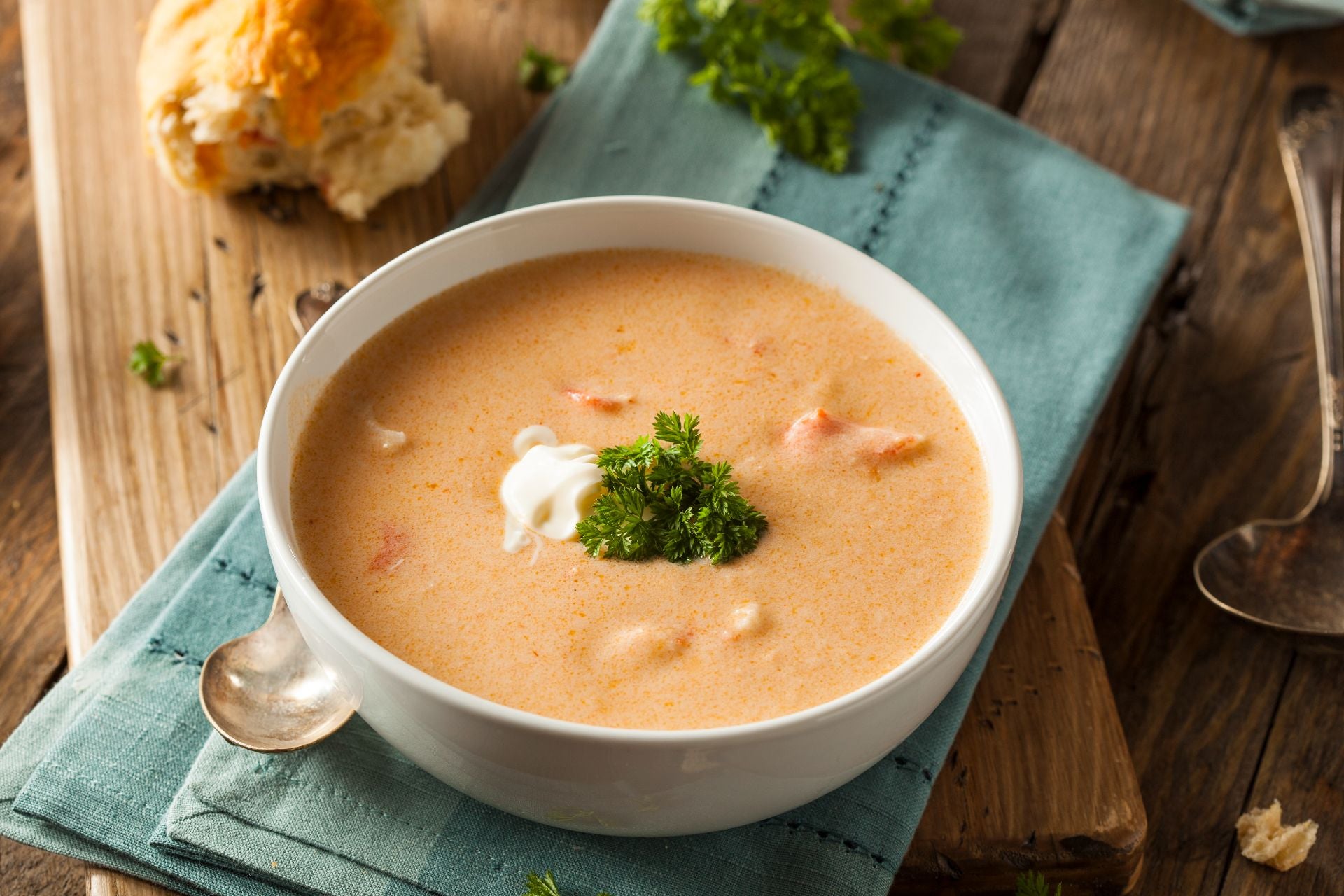 A bowl of bisque with garnish and a piece of torn bread