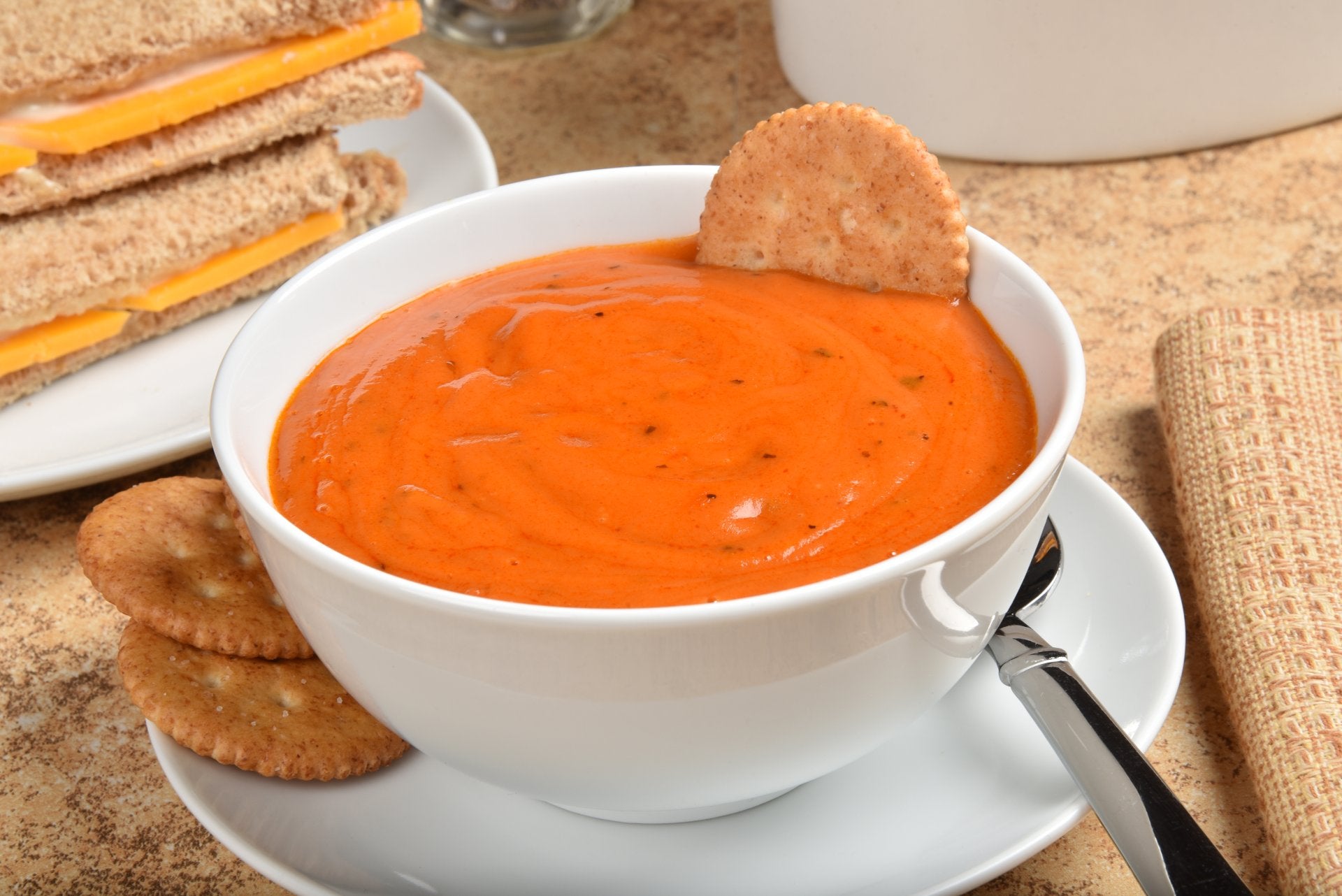 A bowl of vibrant orange bisque with crackers