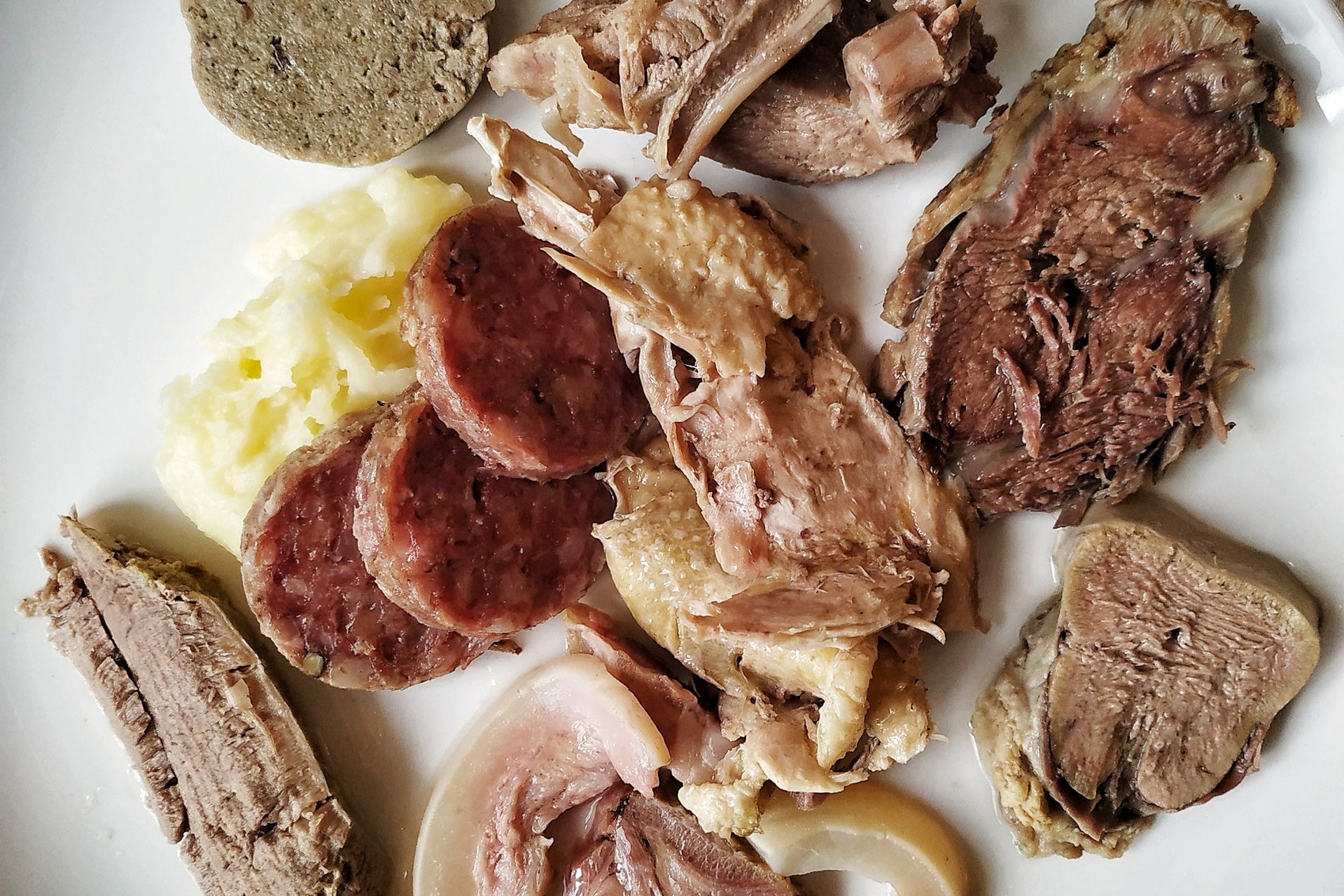 a selection of sliced cooked meats on a plate