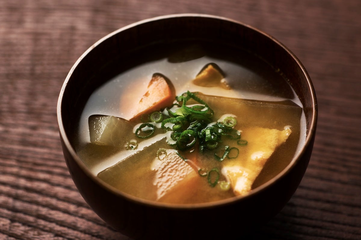A small bowl of fresh miso soup set on a wooden surface