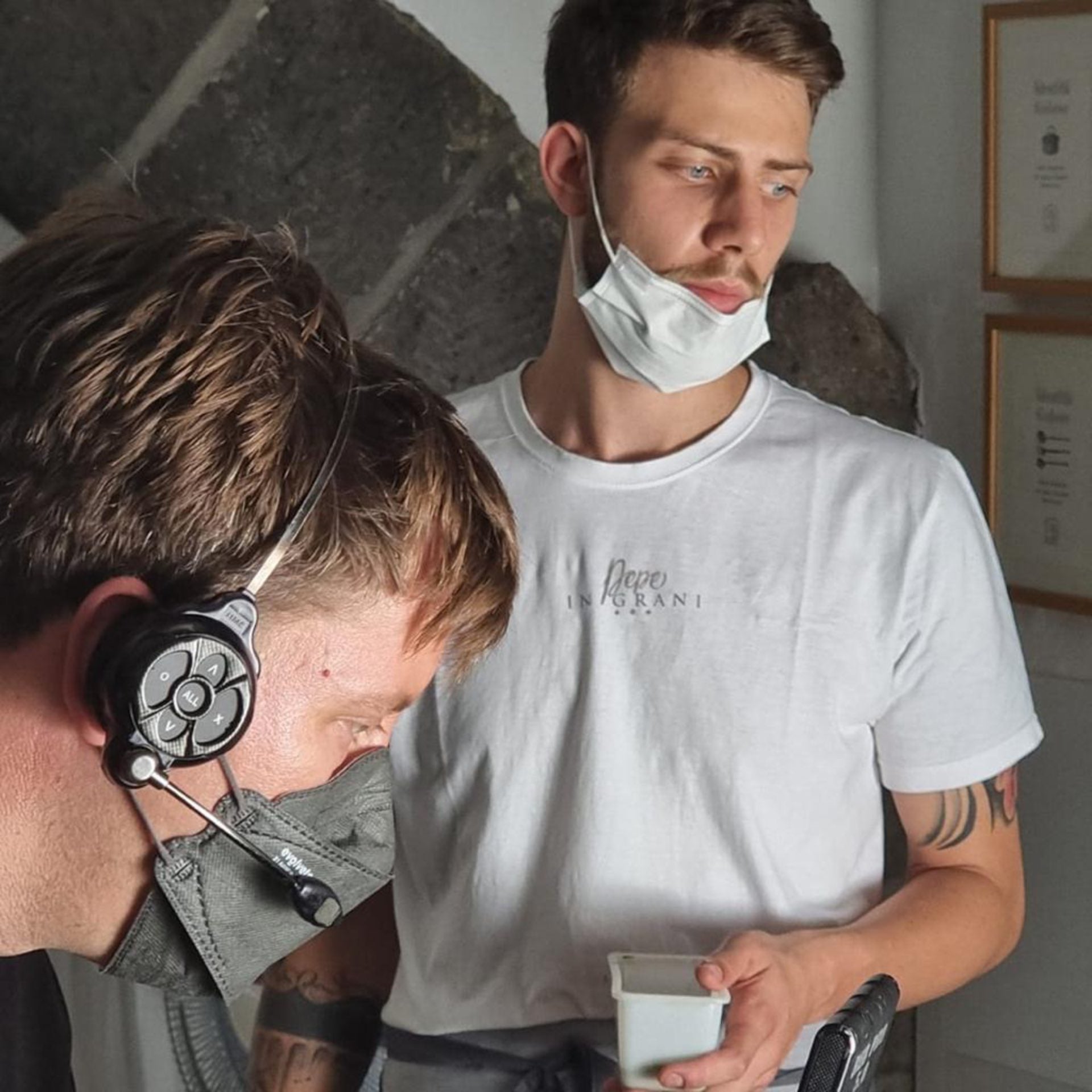 A man in a white shirt wearing a mask and a camera man