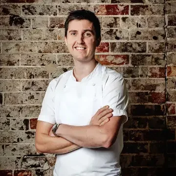 Chef Josh Niland against a brick background.
