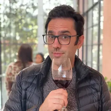 Journalist Paul Feinstein holding a glass of red wine.