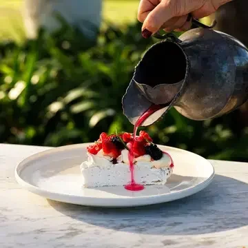Pouring sauce over pavolva at Sara Dining.