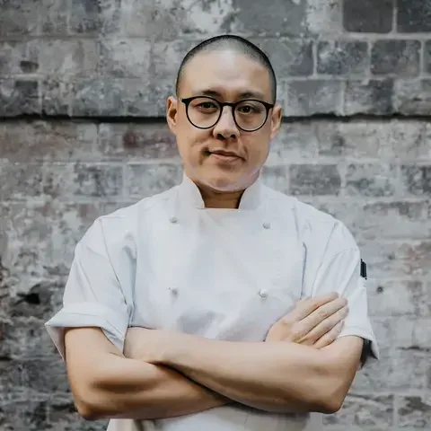 Chef Dan Hong in chef whites with his arms folded.