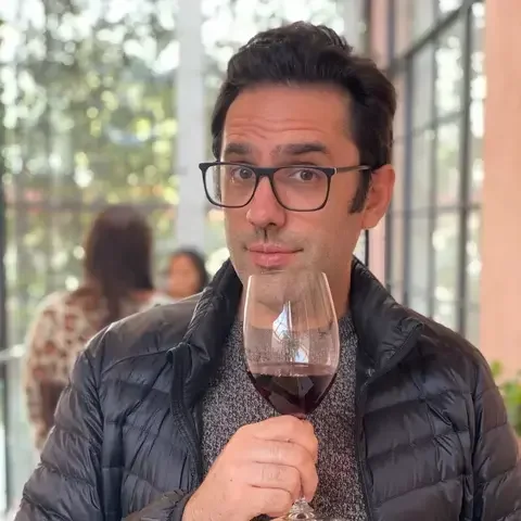 Journalist Paul Feinstein holding a glass of red wine.