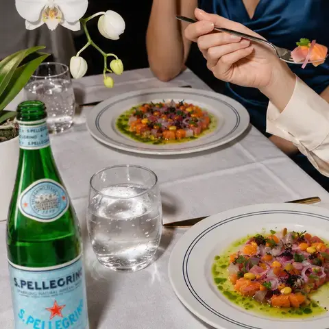 Plates of ceviche on a restaurant table with S.Pellegrino.
