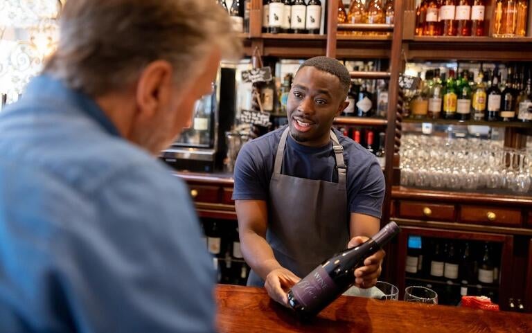 A man ordering a bottle of wine at the bar.
