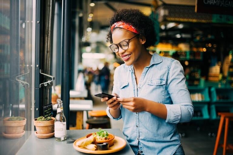 A woman photographing her food with a phone at a restaurant.