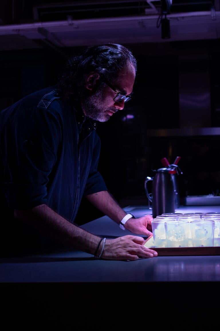 Chef Gaggan Anand working in a darkened kitchen.