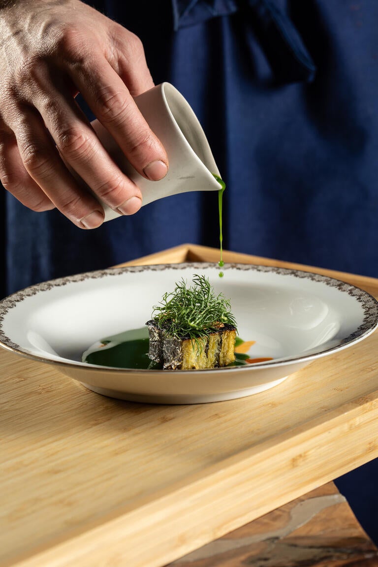 Sauce being poured over a dish at Grow.