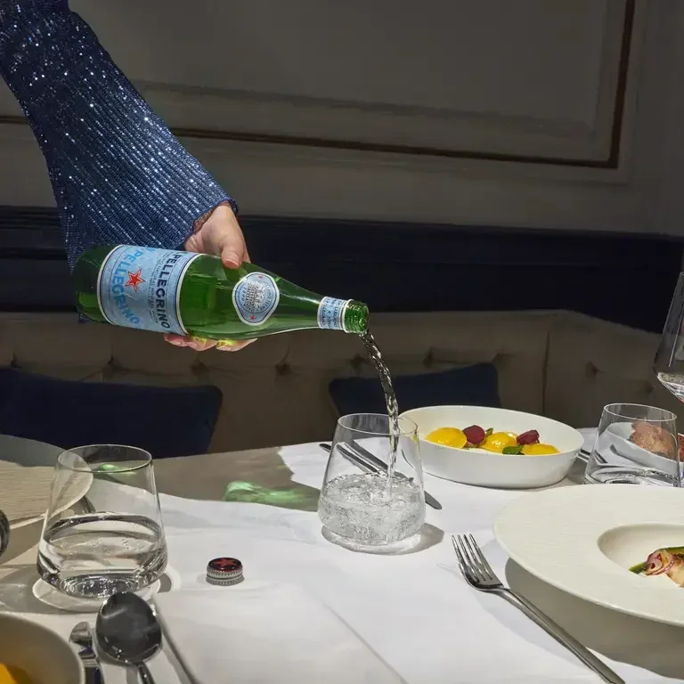 S.Pellegrino being poured at a dining table.