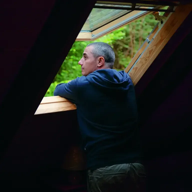 Chef Julien Royer looking out of an open loft space window.