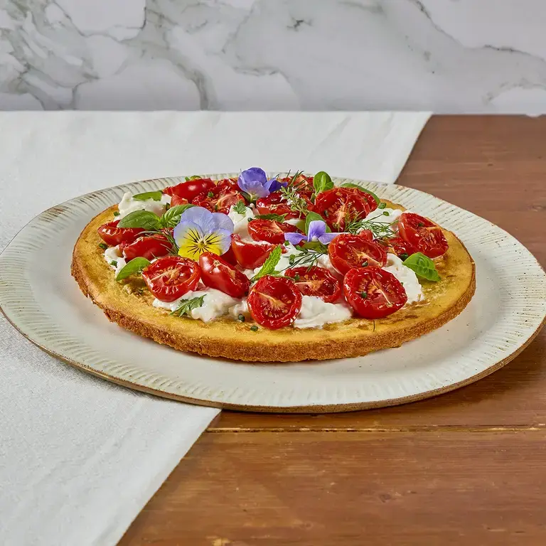 Crispy socca with stracciatella, confit tomatoes and Mediterranean herbs.