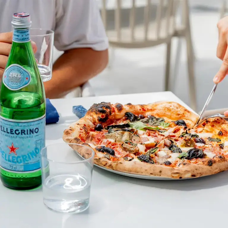 Someone cutting into a capricciosa pizza.