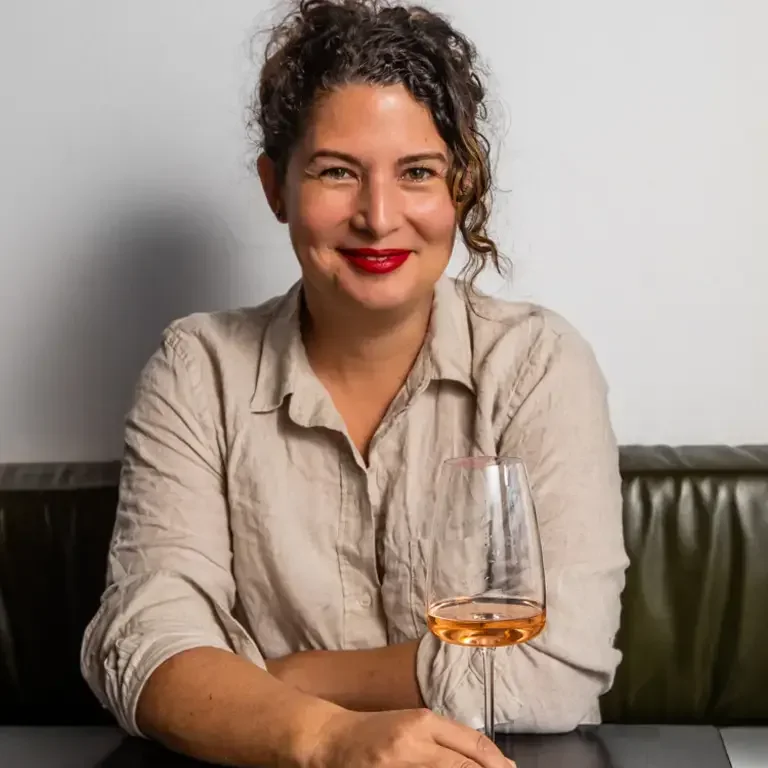 Chef Analiese Gregory smiling with a glass of wine.