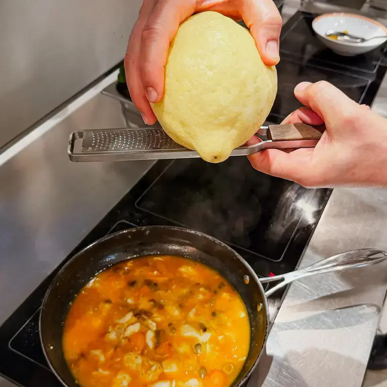 Grating lemon over paccheri with sea bass.