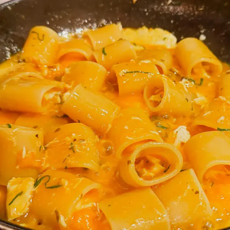 Paccheri with sea bass cooking in a metal pan.