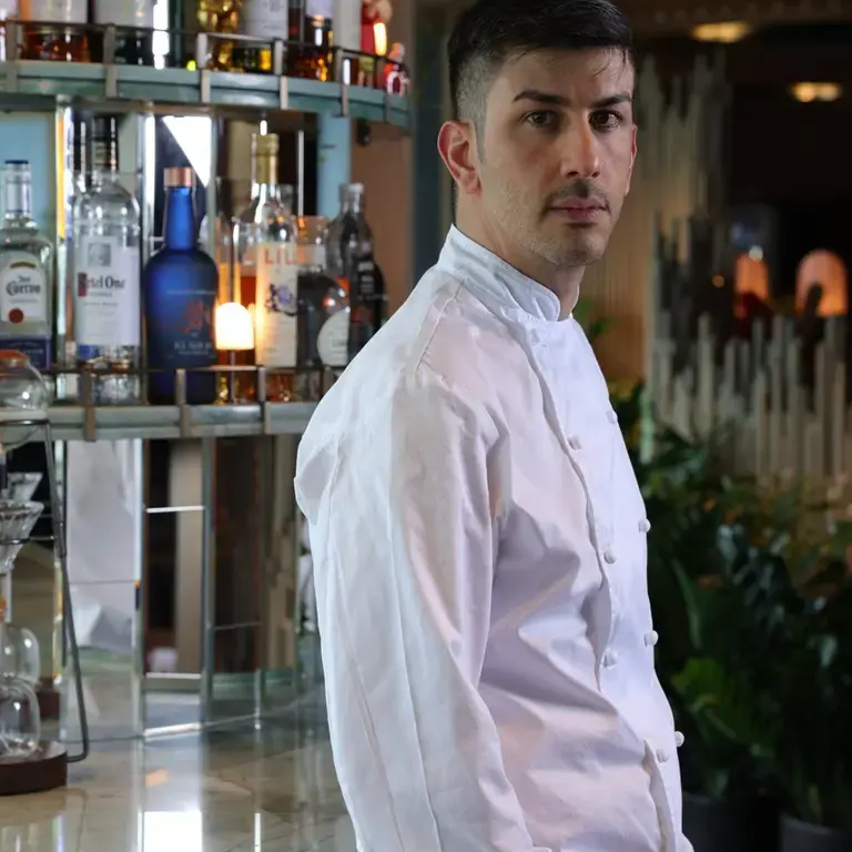 Chef Luigi Troiano leaning against the bar in chef whites.