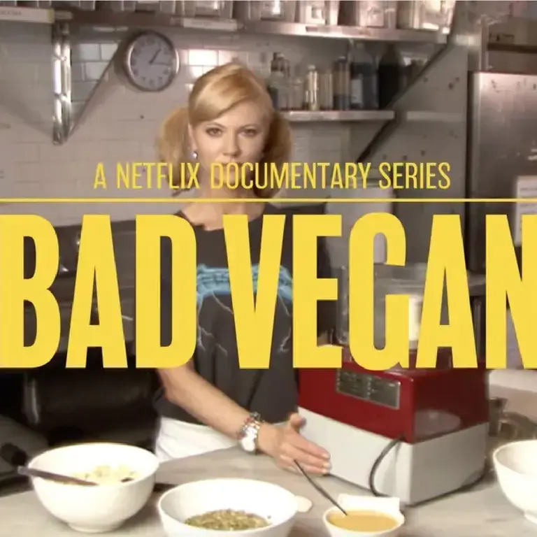 Sarma Melngailis standing in front of a kitchen table surrounded by cooking tools. Yellow text crossing the image