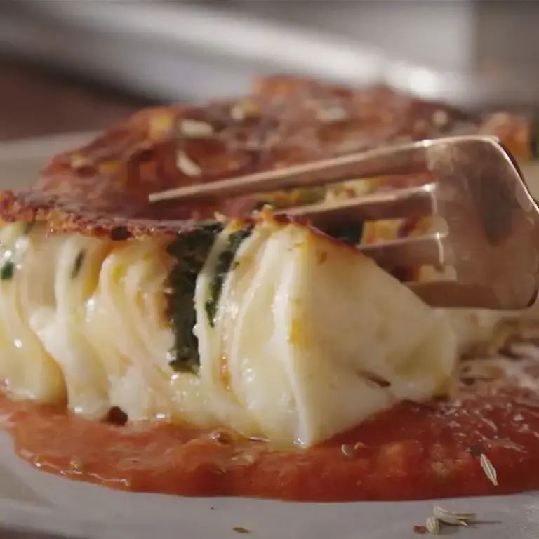 A fork cutting into a 24 layer lasanga on a plate