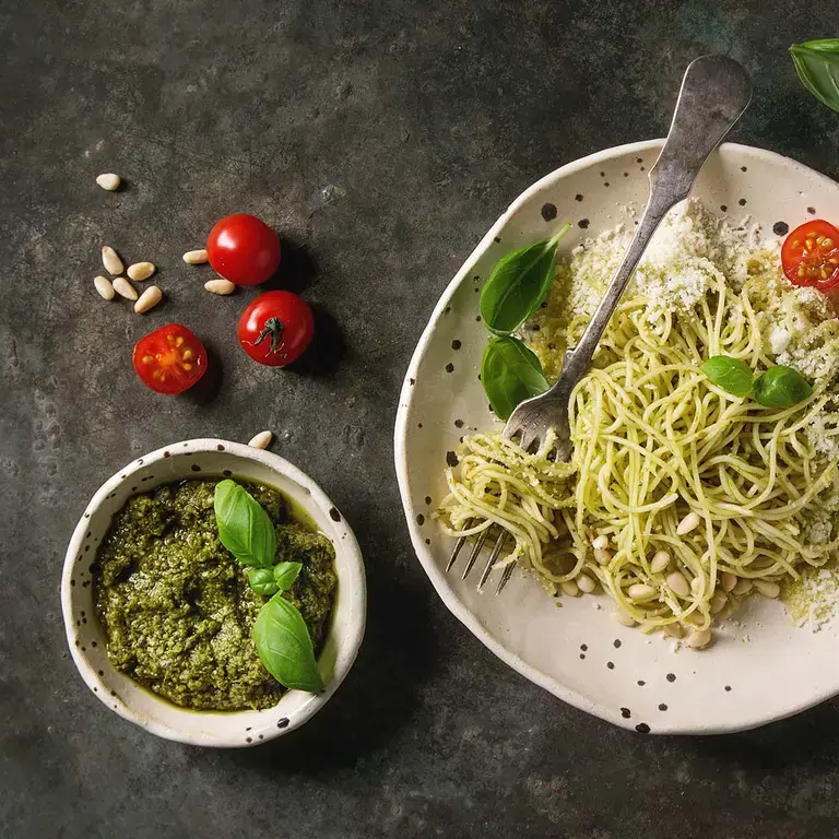 Classic italian spaghetti pasta with pesto sauce, pine nuts, olive oil and fresh basil