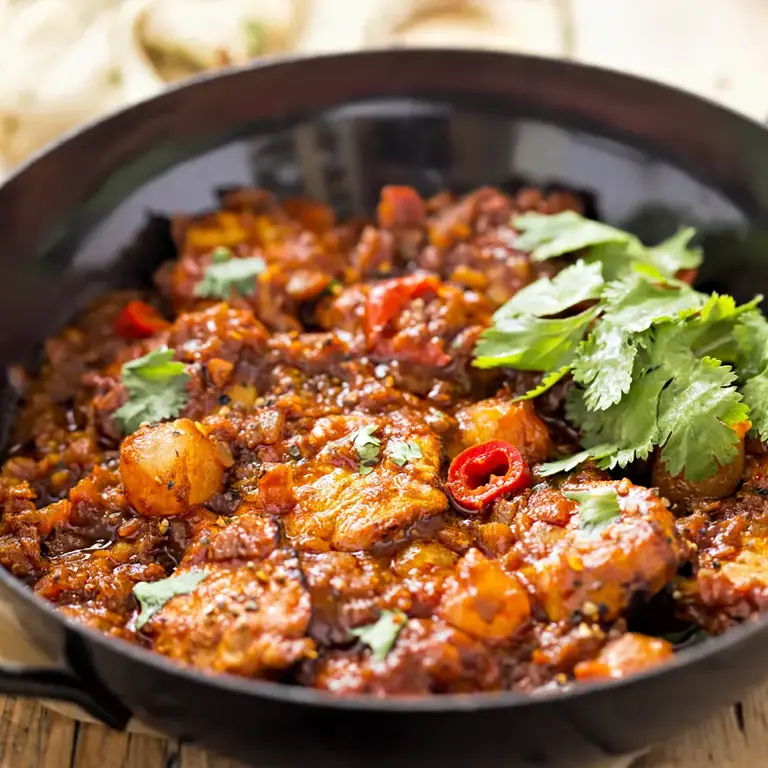 steel balti bowl with handles full of curry with coriander