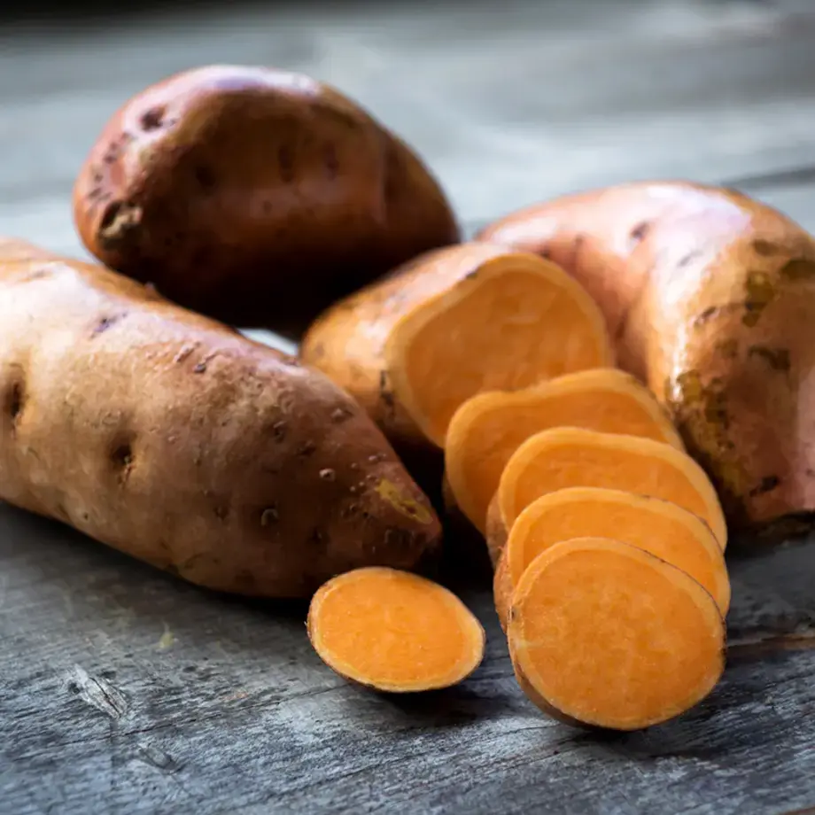 A pile of sweet potatoes, some sliced.