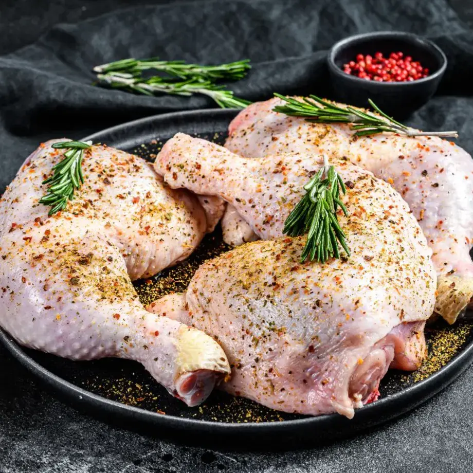 Dish of chicken legs marinating with fresh herbs and spices.