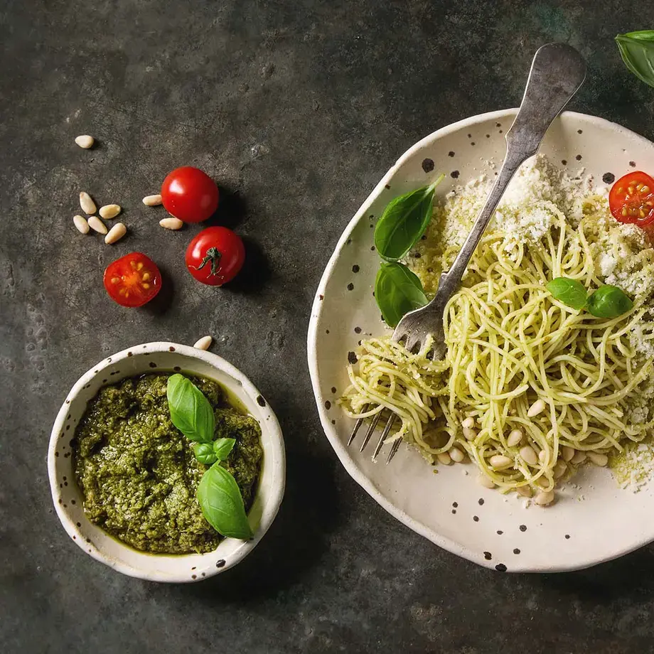 Classic italian spaghetti pasta with pesto sauce, pine nuts, olive oil and fresh basil