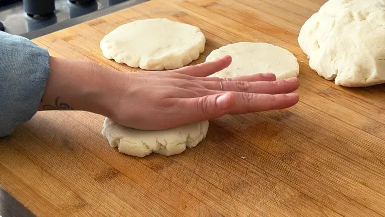Flattening arepas dough.
