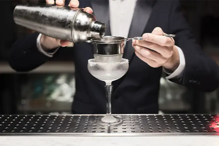 straining the cocktail into a frozen glass