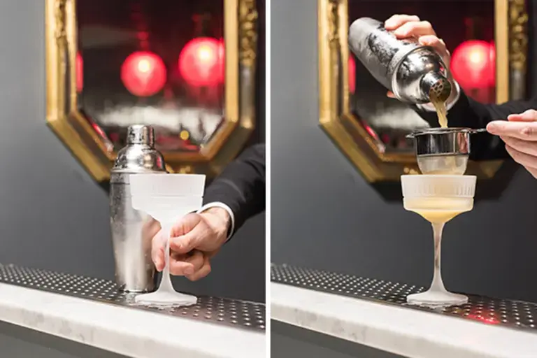 a hand filtering the cocktail into a glass