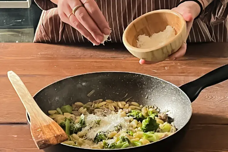 Chef adds grated pecorino Romano to the pan.