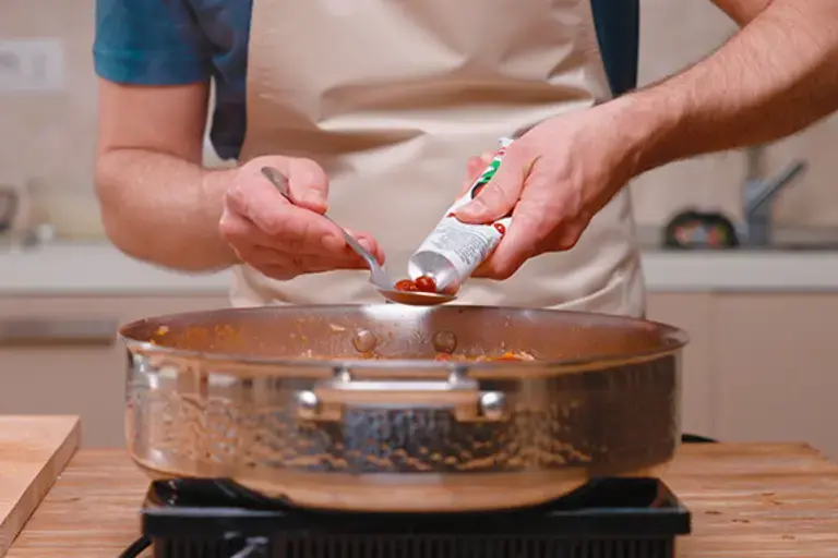Adding tomato paste to the ragù.