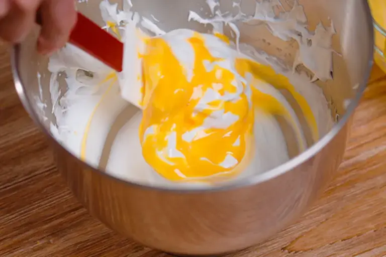 Incorporating yolks into the whipped whites. 