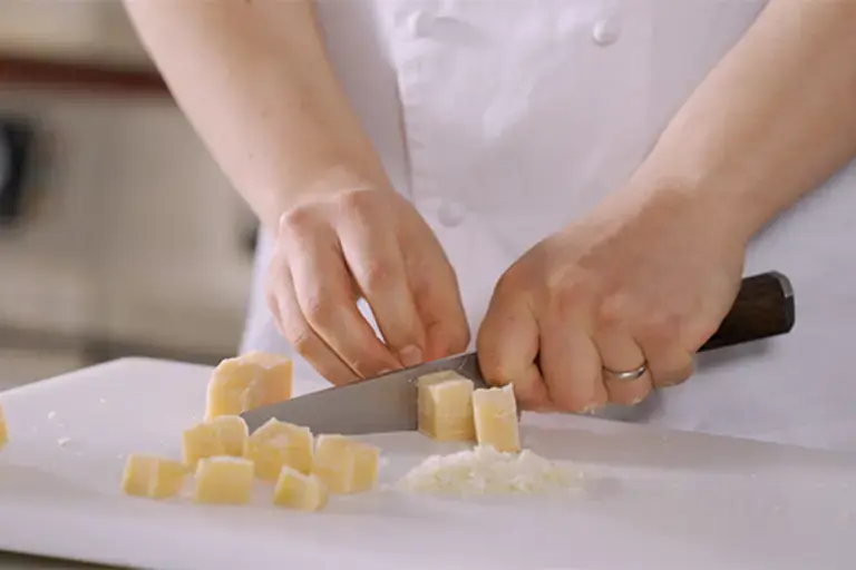 Cheese being chopped into small chunks.